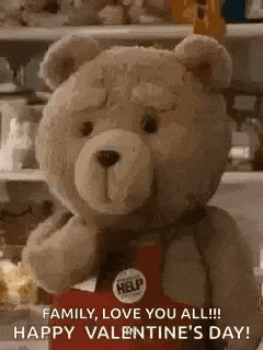 a teddy bear is wearing a red apron and holding a red box .