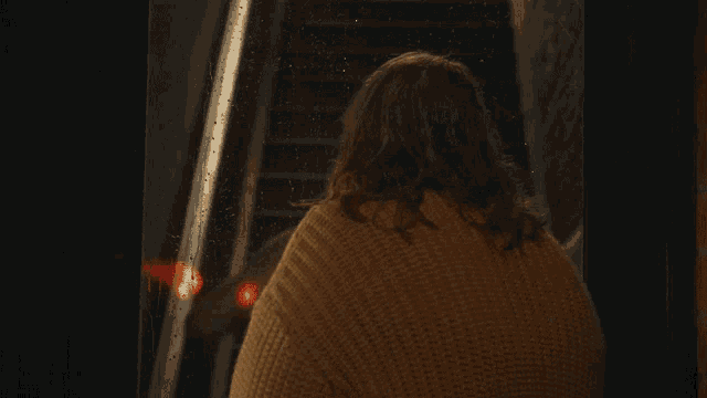a woman in a brown sweater is looking at something
