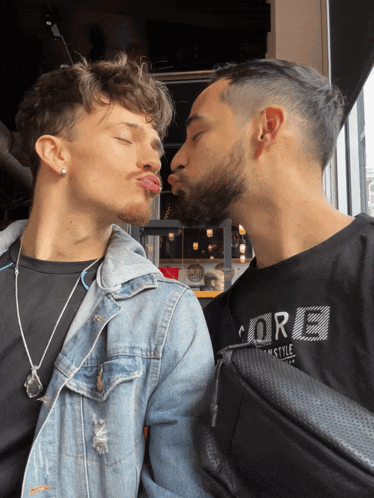 a man wearing a black shirt that says core on it kisses another man