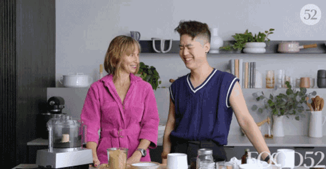 a woman in a pink bathrobe stands next to a man in a blue vest with the number 52 on the bottom