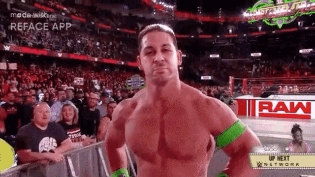 a man without a shirt is standing in front of a crowd at a wrestling event .