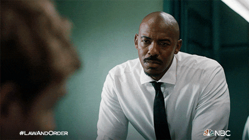 a man in a white shirt and black tie is looking at another man in a nbc poster