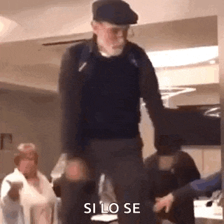 a man in a hat is dancing in a room with people .