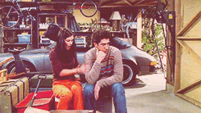 a man and a woman are sitting in a garage talking to each other