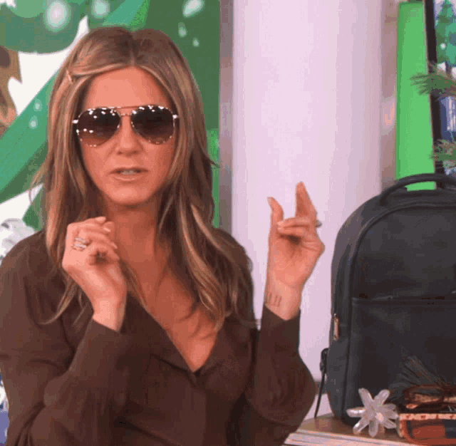 a woman wearing sunglasses has a tattoo on her wrist that says ' j.j.j. '