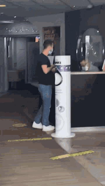 a man wearing a mask is standing next to a trash can that says waste a piece