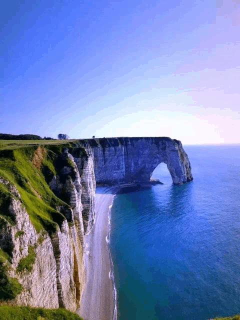 a cliff overlooking the ocean with a large arch