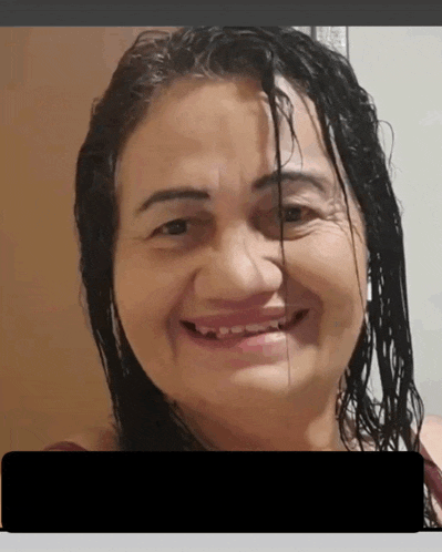 a woman with wet hair is smiling for the camera with a black box in the corner