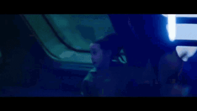 a person is walking down a hallway with a red light coming from the ceiling .