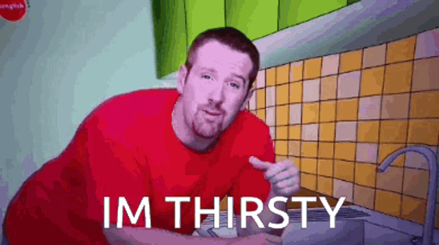 a man in a red shirt says im thirsty in a kitchen