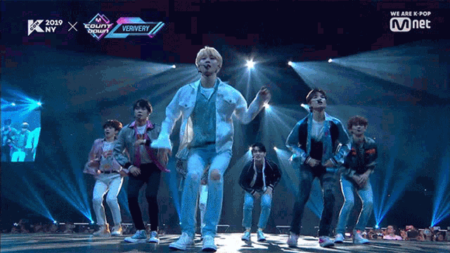 a group of young men are dancing on a stage with a sign that says we are k pop