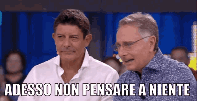 two men are sitting next to each other with the words adesso non pensare a niente above them
