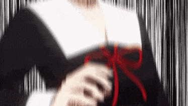 a blurry picture of a girl in a school uniform with a red bow around her neck .