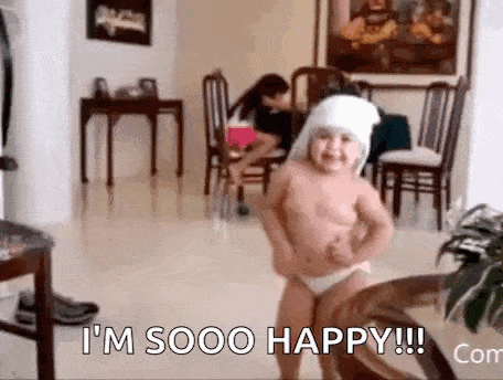 a little girl is dancing in a living room while wearing diapers and a hat .