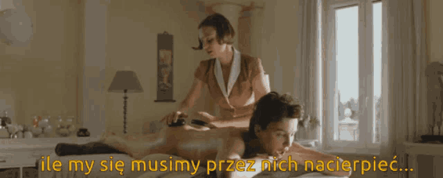 a woman is laying on a bed getting a massage from another woman in a room with a window