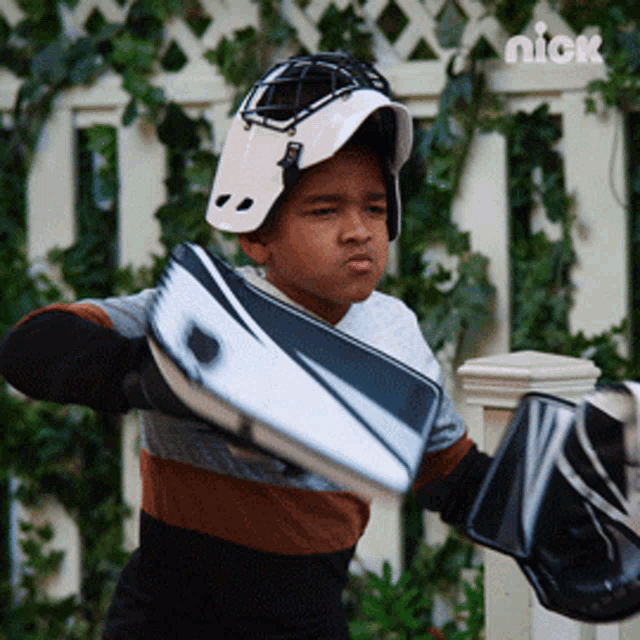 a young boy wearing a helmet and gloves is holding a hockey puck in front of a nick logo