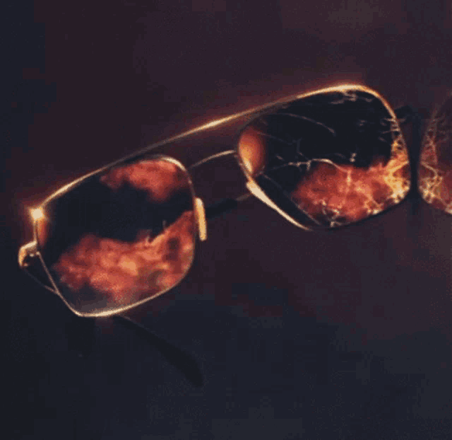 a pair of sunglasses with a broken lens on a dark surface