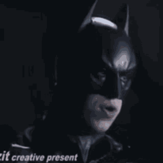a man in a batman costume is making a funny face in the dark