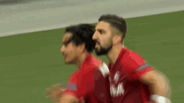 a blurry picture of two soccer players one of whom is wearing a red jersey with the word bull on it