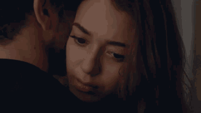 a man with a beard is holding a woman 's head