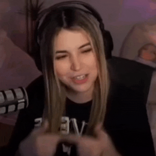 a woman wearing headphones is sitting in front of a microphone and making a funny face .