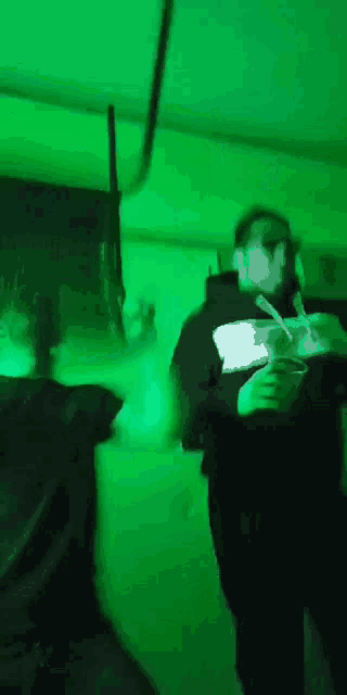 two people are dancing in a room with green lights