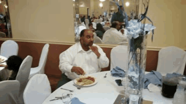 a man is sitting at a table in a restaurant eating a plate of food .