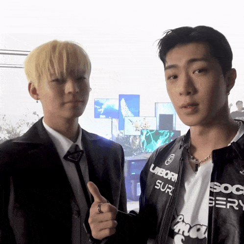 two young men are standing next to each other and one of them is wearing a jacket that says ' unborn sur ' on it