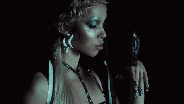 a woman with a nose ring is holding a man 's hand in a dark room .