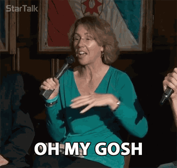 a woman in a green shirt is holding a microphone and saying oh my gosh