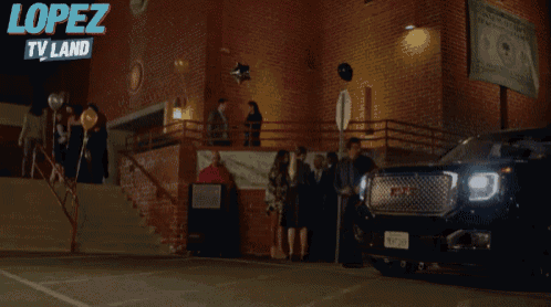 a gmc truck is parked in front of a brick building with a sign that says lopez tv land