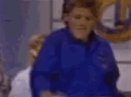 a blurry picture of a group of people standing around a table with a sign in the background that says queen .