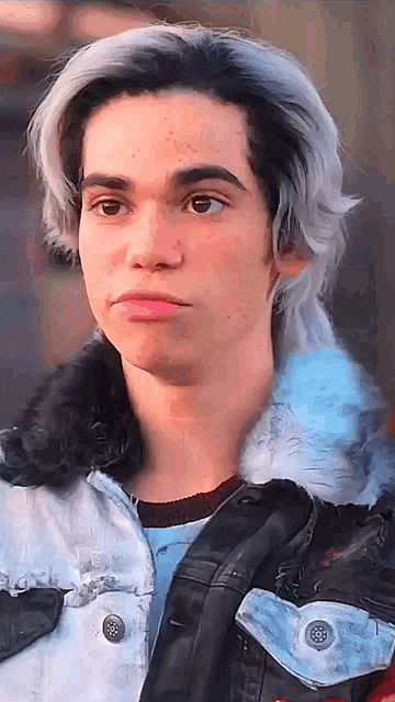 a young man with gray hair and freckles is wearing a jacket