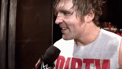 a man wearing a shirt that says dirty is smiling and talking into a microphone
