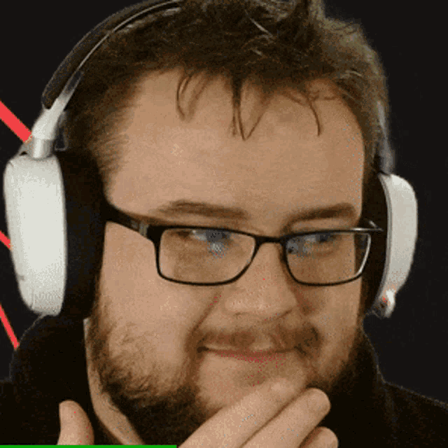 a man with glasses and headphones is smiling with his hand on his chin
