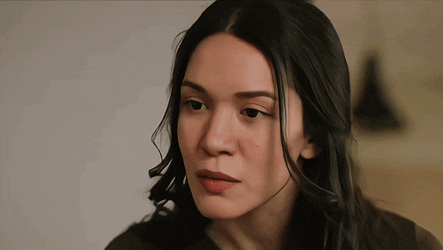 a woman with long black hair looks at the camera