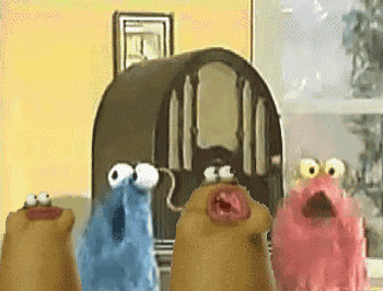 a group of sesame street characters standing around a radio