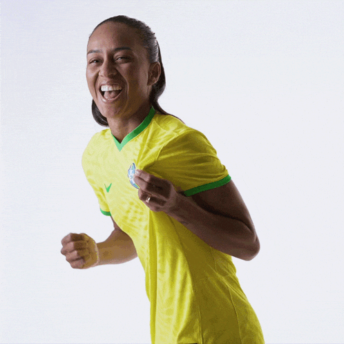 a woman in a yellow shirt is laughing with her fist up