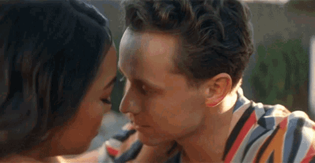 a man and a woman are touching their foreheads and kissing .