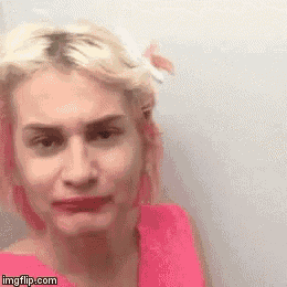 a close up of a woman 's face with pink hair and a pink shirt .