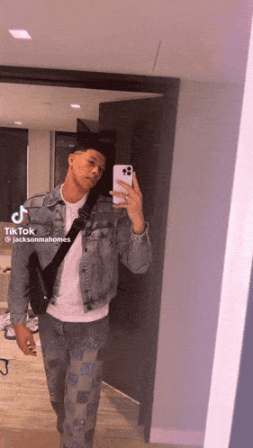 a man in a denim jacket is taking a picture of himself in a mirror ..