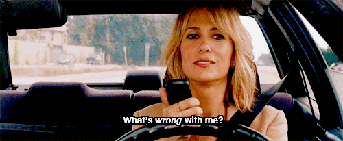 a woman in a car talking on a cell phone with the words what 's wrong with me below her