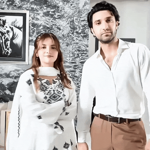 a man and a woman are standing next to each other in front of a painting of a horse