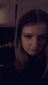 a woman is making a funny face while holding a cup of coffee in front of her face .