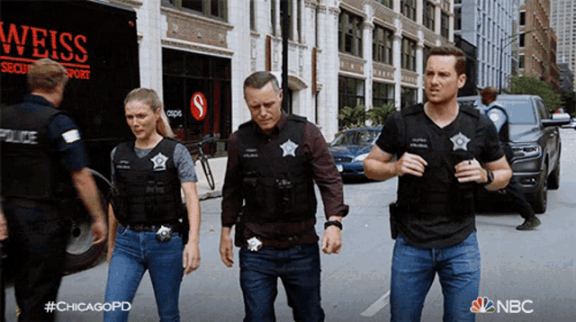 a group of police officers are walking down a street in front of a weiss security transport truck