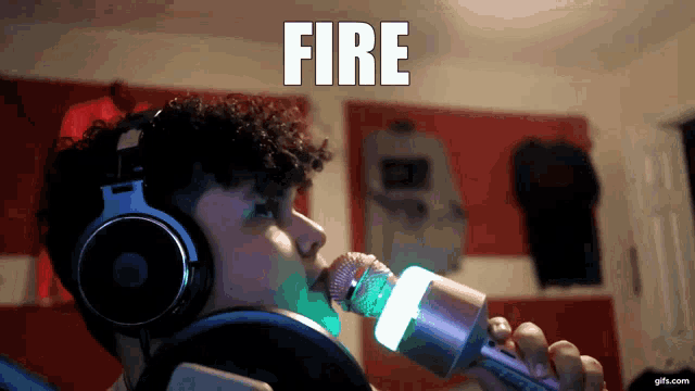 a man wearing headphones is singing into a microphone and the word fire is above him