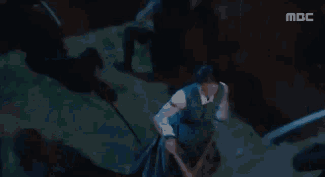 a woman in a traditional korean dress is standing in the dark looking at the camera .