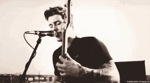 a man is playing a guitar in front of a microphone .