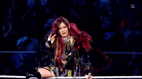 a woman with red hair is standing in a wrestling ring with a rope around her waist .