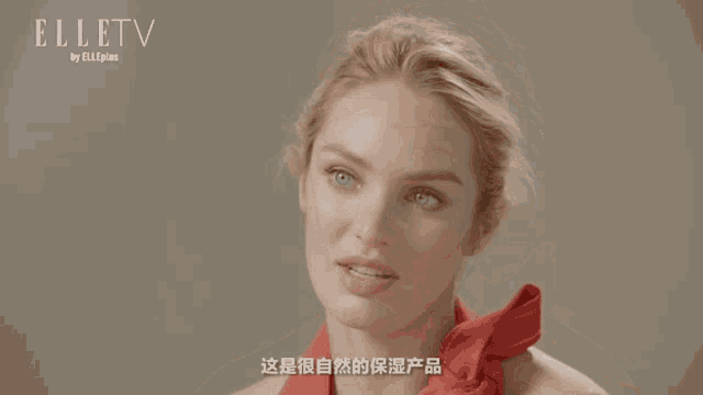 a woman in a red dress is talking in front of an elletv ad